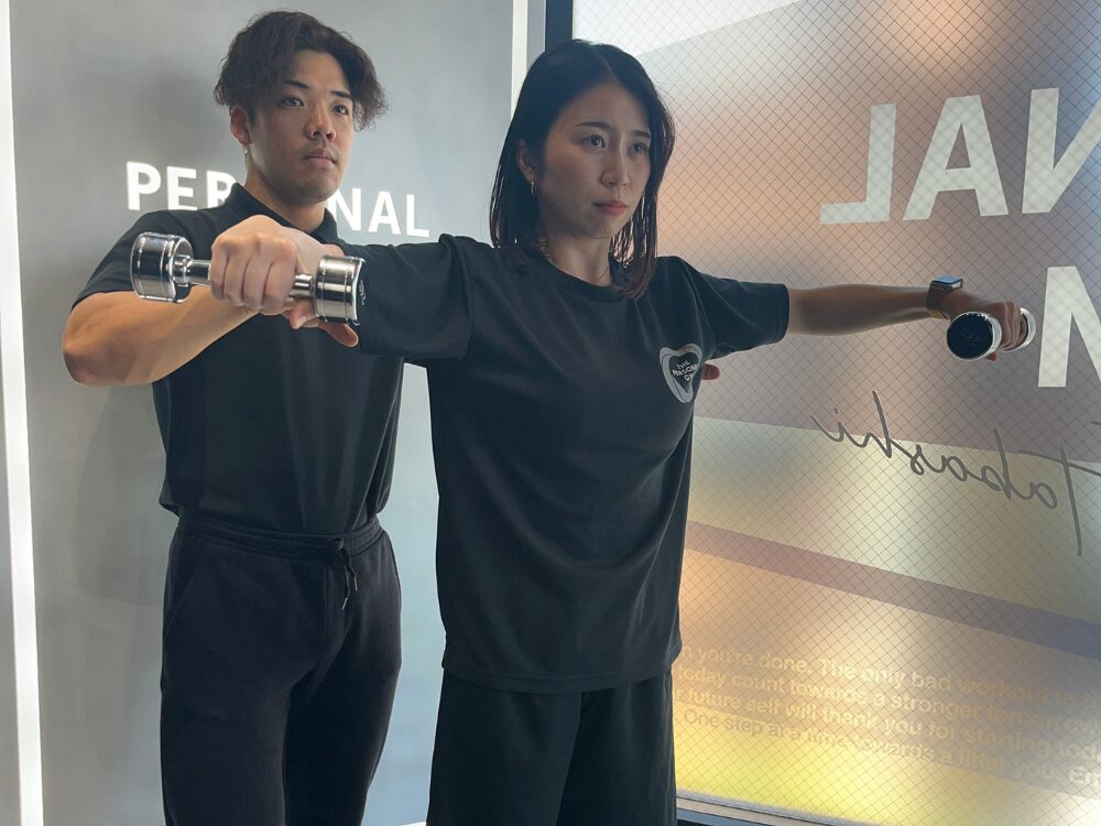 トレーナーがお客様に方のトレーニングを教えている