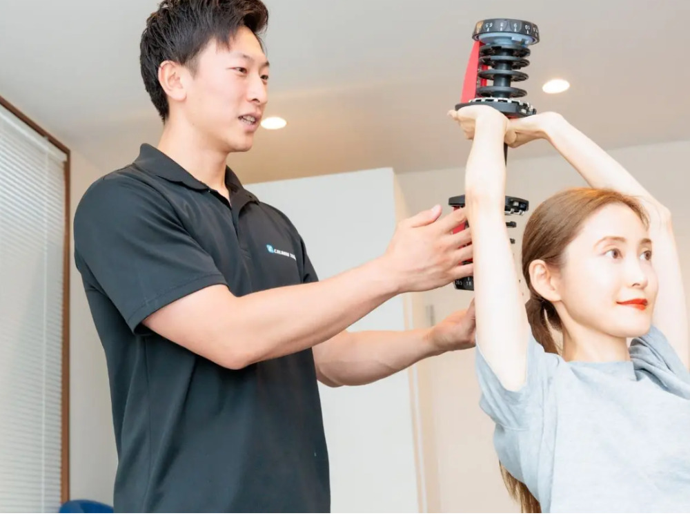 CALORIE TRADE JAPANにて女性がフレンチプレスのパーソナルトレーニングを受けている写真
