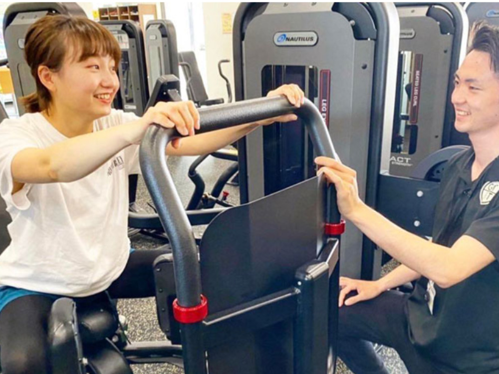 ゲットフィット仙台店にて女性がレッグプレスの指導を受けている写真