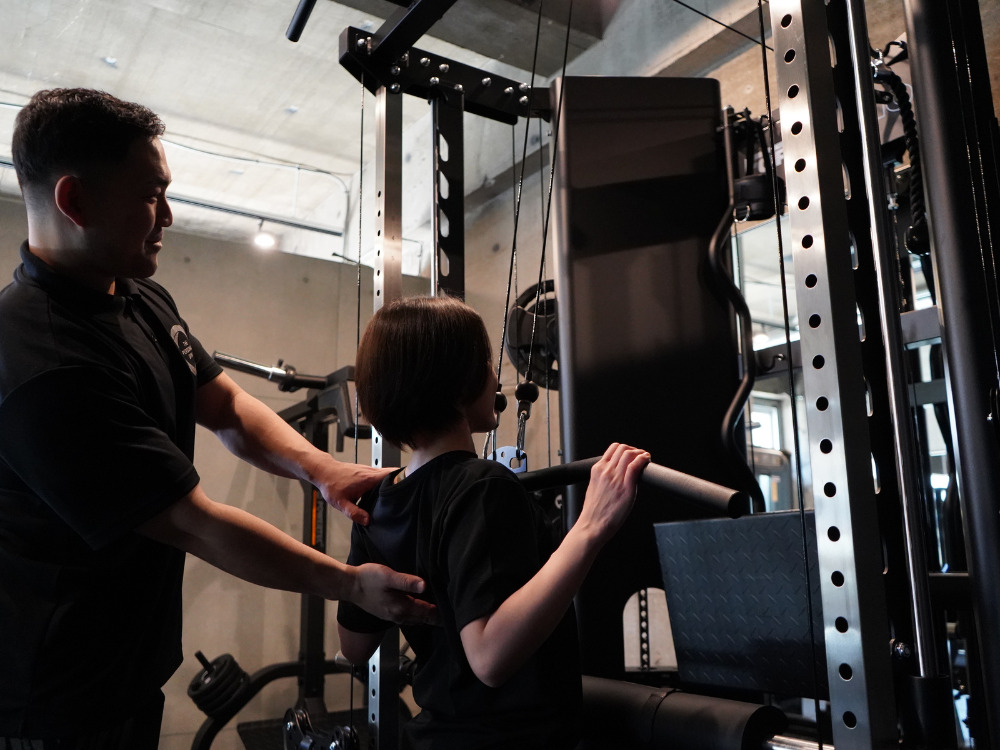 THE PERSONAL GYM（ザ　パーソナルジム）綾瀬店でトレーニングしている女性とトレーニングを教えている男性