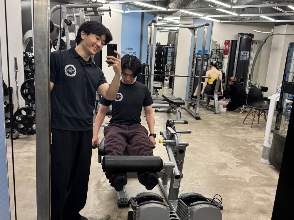 男性がレッグエクステンションをしている写真