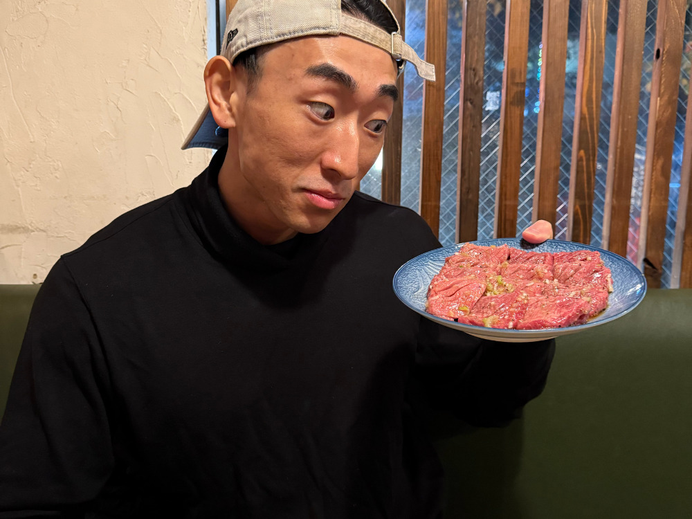 焼肉を掲げる男性の写真