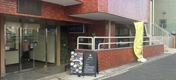 右手の赤い建物の地下1階になります。螺旋階段をおりますとございます。