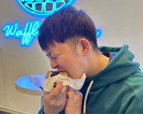 朝比奈トレーナーがハンバーガーを食べている写真