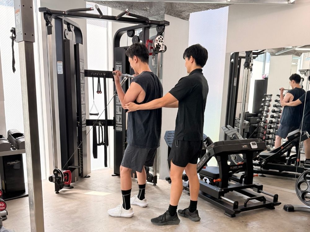 男性のお客様がトレーナーと腕のトレーニングをしている様子