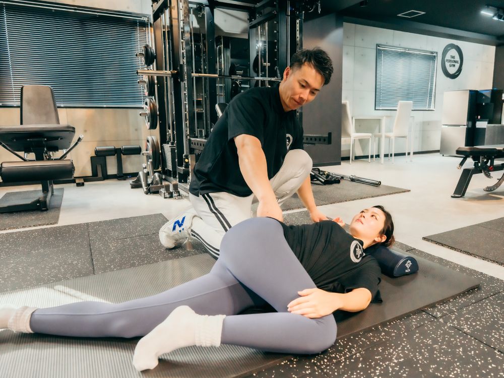 女性のお客様の姿勢改善のためストレッチをサポートする門前仲町パーソナルトレーニングの様子