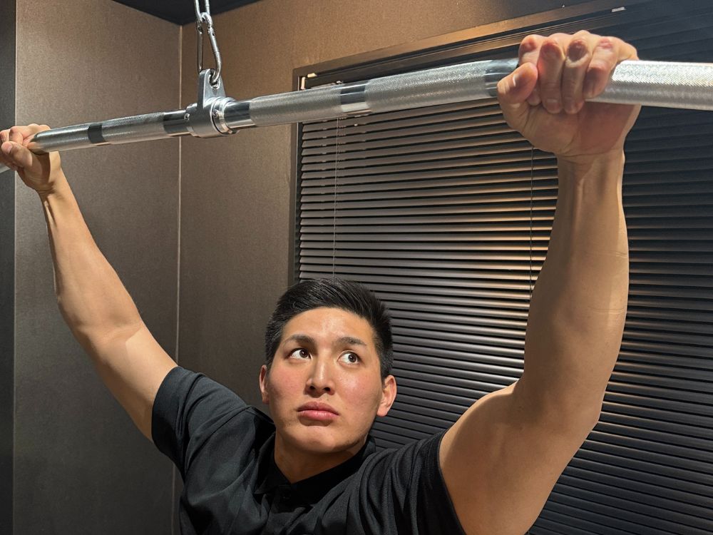 門前仲町エリアのパーソナルジムで、小泉トレーナーが背中のパーソナルトレーニングの説明をしている様子