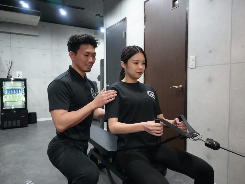 トレーナーがお客様に背中のトレーニングを教えている