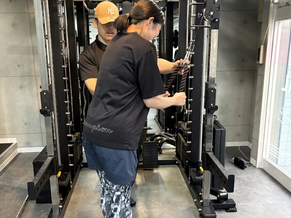 トレーナーがお客様に腕のトレーニングを教えている