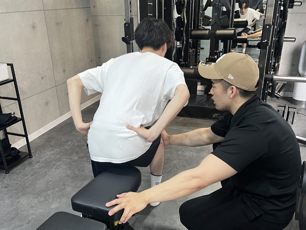 トレーナーがお客様に脚のトレーニングを教えている