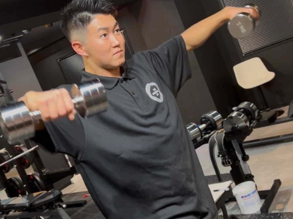 門前仲町のパーソナルジムでダンベルを使ったトレーニング指導を行うトレーナー山崎