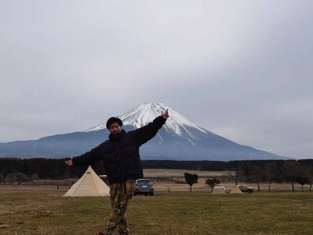 吉田トレーナーが富士山のふもとでポーズをしている