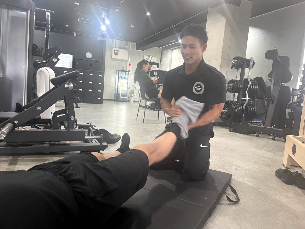 THE PERSONAL GYM薬院店でトレーナーがお客様の身体の状態に合わせて丁寧にサポートしている様子