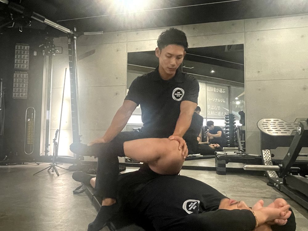 THE PERSONAL GYM薬院店でトレーナーがお客様の柔軟性に合わせてストレッチ指導をしている様子