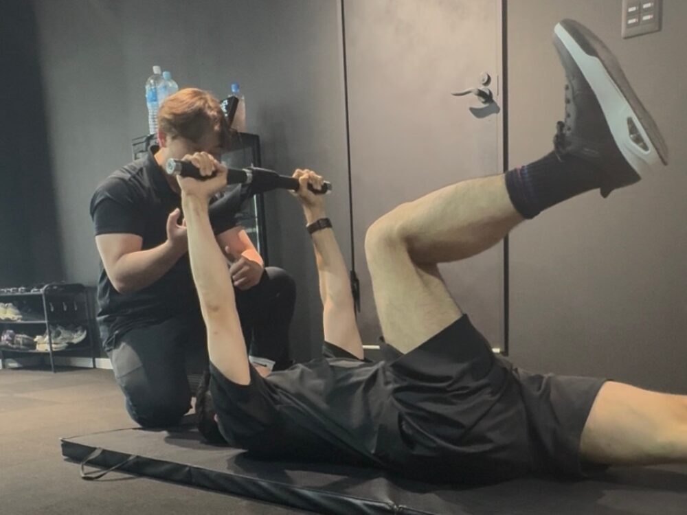 THE PERSONAL GYM武蔵小杉店でデットバグを指導するトレーナーと40代男性
