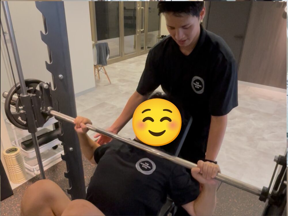 お客様がトレーニング、トレーナーが補助している写真