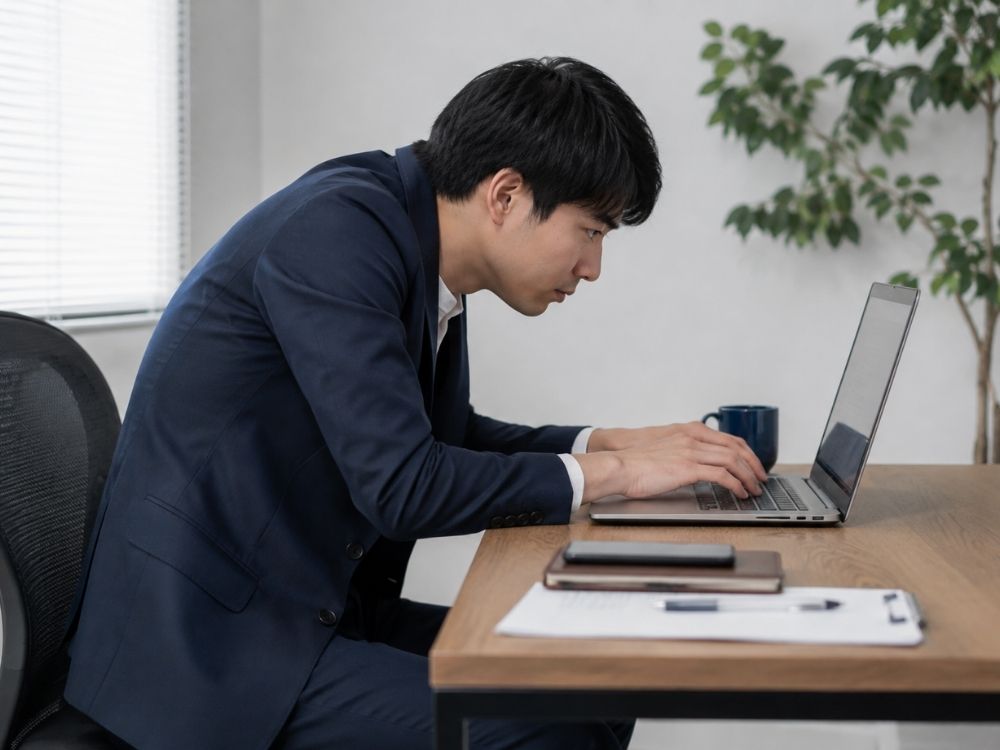姿勢悪くパソコンいじる男性