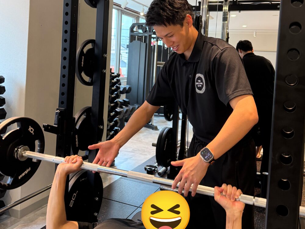 お客様のベンチプレスをトレーナーが補助している写真