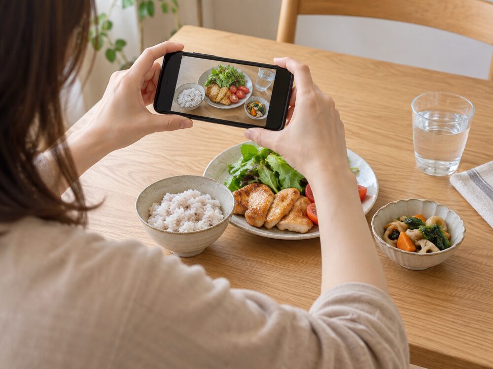 食事内容を記録するため、スマートフォンで料理を撮影するイメージ